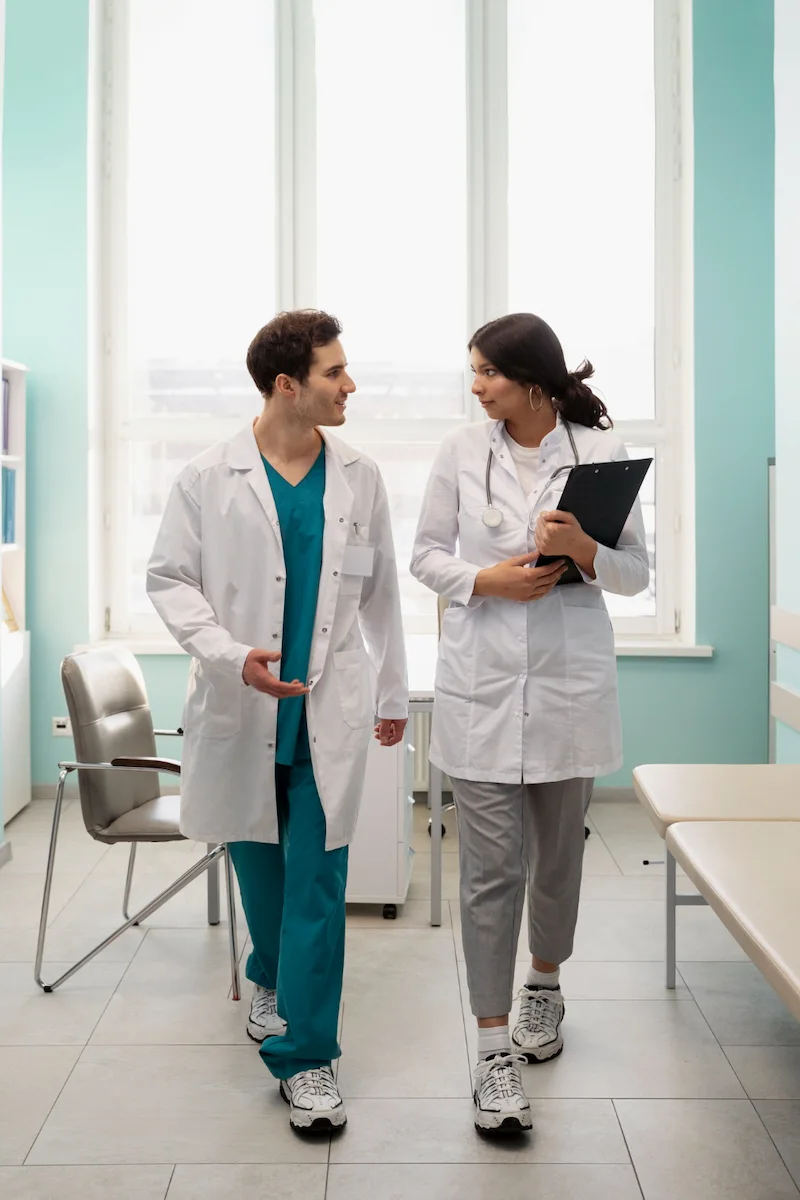 Male and female doctors walking in hospital discussing patient care and medical treatment plans
