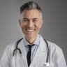 Smiling male doctor in white coat and stethoscope offering professional healthcare services