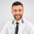 Young male doctor in white coat smiling and ready to assist patients