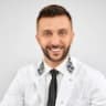 Young male doctor in white coat smiling and ready to assist patients